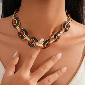 Détail d'un collier vintage doré avec segments en émail noir et cristal ambré