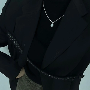 Detail of a minimalist S925 silver baroque pearl necklace on a chic black blazer outfit