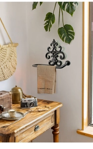 Detailed view of vintage black cast iron towel rack with ornate fleur-de-lis wall mount