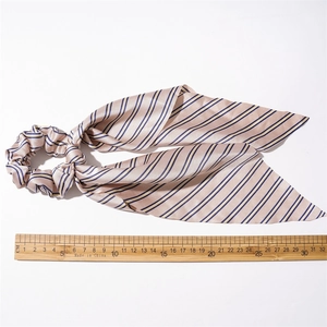 Detailed macro view of pink satin scrunchie with blue and yellow stripes and long streamers