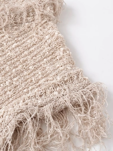 Close-up detail of knitted vest texture with intricate crochet patterns and fringe trim