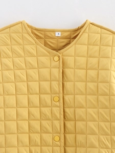 Détail du col rond et de la fermeture à boutons de la veste matelassée jaune