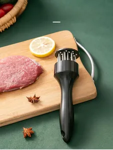 Close-up of stainless steel meat tenderizer needles on a wooden board with fresh steak