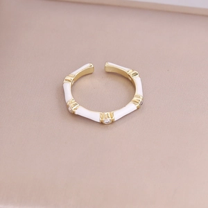 Detail view of bamboo-style gold ring with white enamel accents and small rhinestones