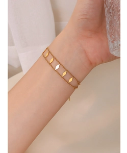 Double-layered 18k gold plated titanium bracelet featuring geometric rhombus charms on model