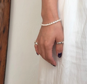 Close-up of 925 sterling silver heart ring and freshwater pearl bracelet on a wrist