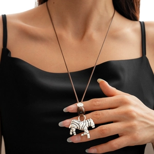 Detail of silver zebra pendant on brown woven cord necklace worn by a model