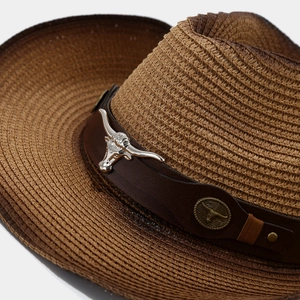 Close-up of Western straw hat featuring a leather band and silver longhorn bull skull emblem