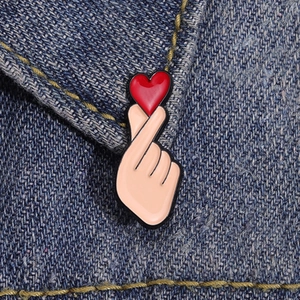 Cartoon finger heart enamel pin badge with red heart on a blue denim jacket lapel