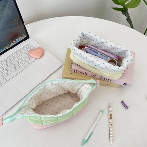 Detailed view of quilted pencil cases with colorful star lining on a white desk