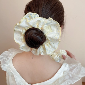 Floral fabric hair scrunchie with lace trim shown on a bun hairstyle for women