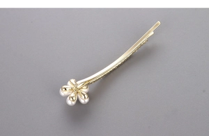 Macro shot of elegant golden hair clip featuring a white five-petal pearl flower design