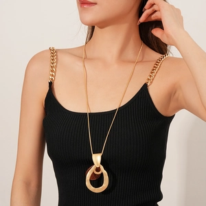 Fashionable long golden necklace with red-brown round pendant worn on a model