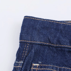 Gros plan détaillé du tissu denim bleu foncé avec doubles coutures orange contrastées