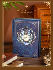 Detail view of vintage dark blue notebook cover with gold foil compass and floral patterns