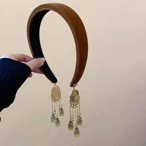 Detailed view of brown velvet headband with vintage gold bell fringe tassels