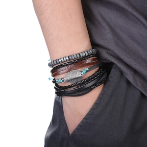 Détail d'un bracelet multicouche en cuir avec breloque feuille argentée au poignet