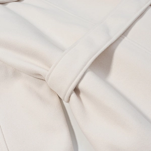 Close-up of cream white wool coat belt knot showing high-quality stitching and texture