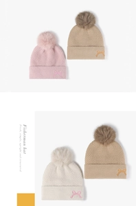 Detail der Strickmütze mit Plüschbommel und feiner Schleifenstickerei-Struktur