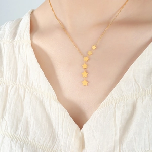 Elegant gold Y-shaped necklace featuring five linked stars on a model with a white shirt