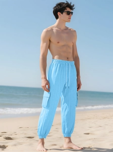 Men's light blue cargo pants with textured fabric and drawstring cuff on a sunny beach