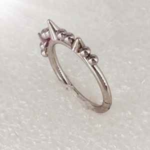 Close-up of 316L stainless steel body piercing ring with beads and sharp spike details