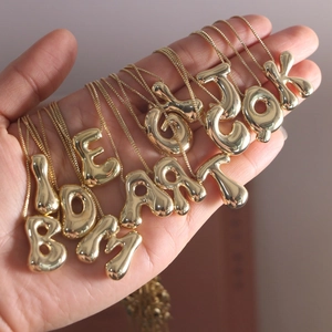 Detail of 18K gold plated balloon bubble initial pendants on elegant thin chains