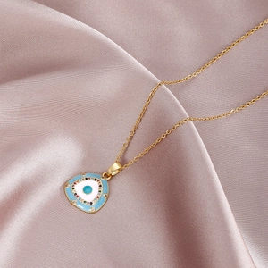 Close-up of golden triangle evil eye pendant with blue enamel and sparkling cubic zirconia