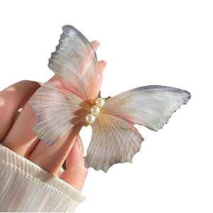 Delicate butterfly hair clip with gradient tulle wings and pearl accents in hand