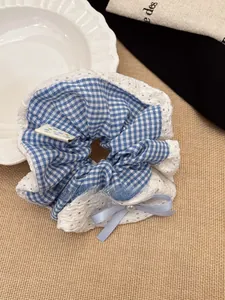 Close-up of blue plaid scrunchie with lace trim, satin bow and pearl detail decoration