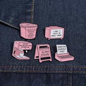 Dettaglio di spille in smalto rosa con macchina da scrivere e caffè su tessuto denim
