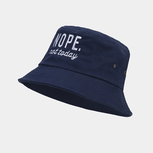 Detail of navy blue cotton bucket hat with white 'NOPE' embroidery and metal eyelets