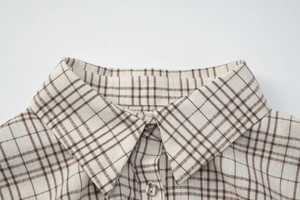 Close-up of classic brown checkered shirt collar and button details on plaid fabric
