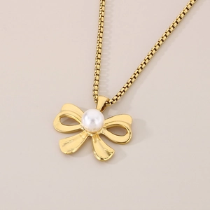 Detailed view of a gold bow pendant with a round pearl on a square link chain