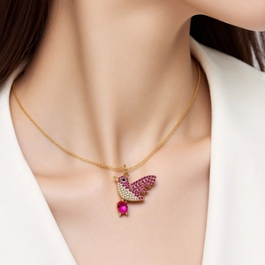 Detail of a hummingbird pendant with pink and white cubic zirconia on a gold chain