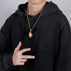 Close-up of a golden owl pendant with twist chain worn on a black streetwear hoodie