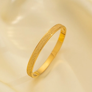 Mattierter 18k vergoldeter Edelstahl-Armreif auf eleganter cremefarbener Seide