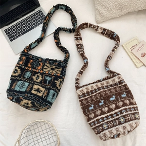 Two patterned plush bucket bags displayed with a laptop and books on white bedding