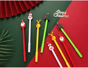 Close-up of Christmas gel pens with silicone Santa and reindeer toppers on red-green background