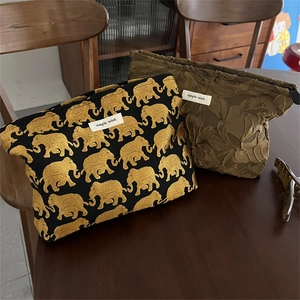 Detailed view of vintage jacquard makeup bags with golden elephant and floral patterns