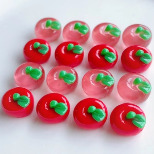 Macro view of mini resin apple charms in red and pink for DIY crafts and hair clips