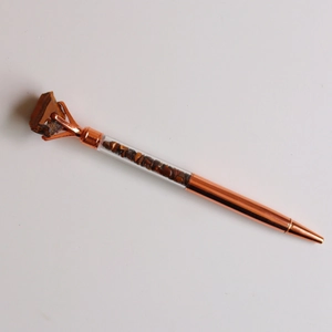 Macro view of rose gold crystal pen featuring raw tiger eye stone and碎石 filling