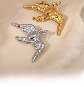 Detail of golden and silver dove brooches on a textured ceramic dish in soft lighting