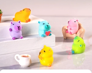 Close-up of colorful resin Capybara miniatures in various poses with tiny sofa props