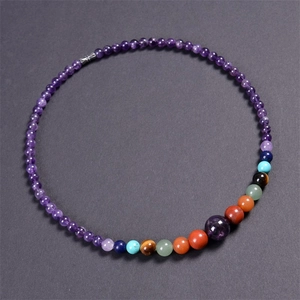 Macro shot of 6mm purple amethyst beads with colorful chakra stones on dark background