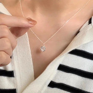 Close-up of a 925 sterling silver necklace with a round zircon pendant on a model