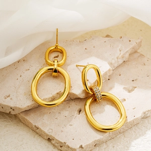 Detail of 18K gold double hoop earrings with cubic zirconia on a minimalist stone base