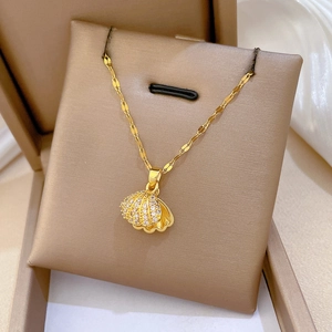 Close-up of a gold shell pendant necklace with cubic zirconia in a beige jewelry box