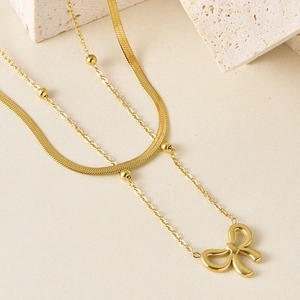 Détail du collier double rang doré avec chaîne serpent et pendentif nœud papillon