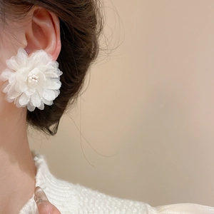 Elegant white tulle flower earrings with pearl core detail worn by a model in a side view